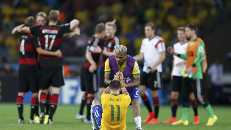 Brazil's Oscar is consoled by Alves after they lost to Germany in their 2014 World Cup semi-finals at the Mineirao stadium in Belo Horizonte