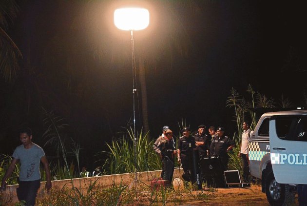 Abdul Rahim (third left) and Mazlan (second right) at the scene of the crime in Simpang Ampat. — Malay Mail pic