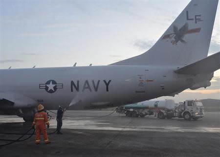 Aviation Structural Mechanic 2nd Class Matthew Walton sprays down a P-8A Poseidon with fresh water before its flight to assist in search and rescue operations for missing Malaysia Airlines flight MH370 in Kuala Lumpur March 18, 2014, in this U.S. Navy handout photo. REUTERS/U.S. Navy/Mass Communication Specialist 2nd Class Eric A. Pastor/Handout via Reuters