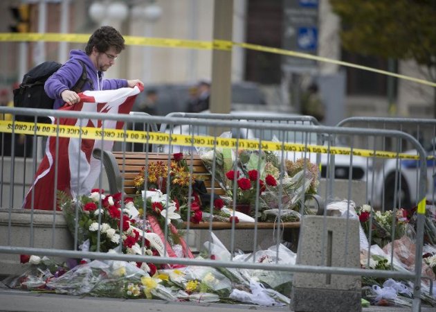 Un hombre coloca una bandera de Canadá en el Monumento Nacional de Guerra este jueves 23 de octubre en Ottawa, al día siguiente del atentado