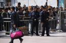 A passenger walks past police at the exit of the   South Railway Station in Urumqi