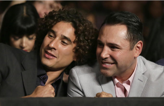 Mexican National team goalie Guillermo Ochoa, left, and former boxing champion Oscar De Le Hoya watch Abner Mares and Jonathan Oquendo during their featherweight fight, Saturday, July 12, 2014, in Las