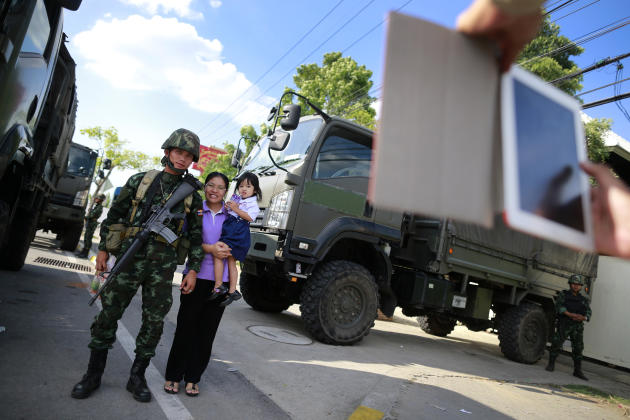 A Thai mother and daughter have their photograph taken with a soldier guarding the area near a pro-government demonstration site on the outskirts of Bangkok, Thailand Wednesday, May 21, 2014. Thailand