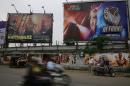 Commuters move past posters and hoardings of Indian films in Mumbai, India, Tuesday, Aug 19, 2014. Police say they have arrested the head of India's film censorship board for allegedly taking bribes in exchange for speeding up the approval of a film.(AP Photo/Rafiq Maqbool)