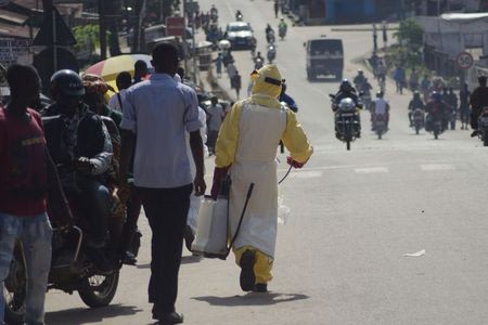 A health worker with disinfectant spray walks down a street outside the government hospital in Kenema, July 10, 2014. REUTERS/Tommy Trenchard