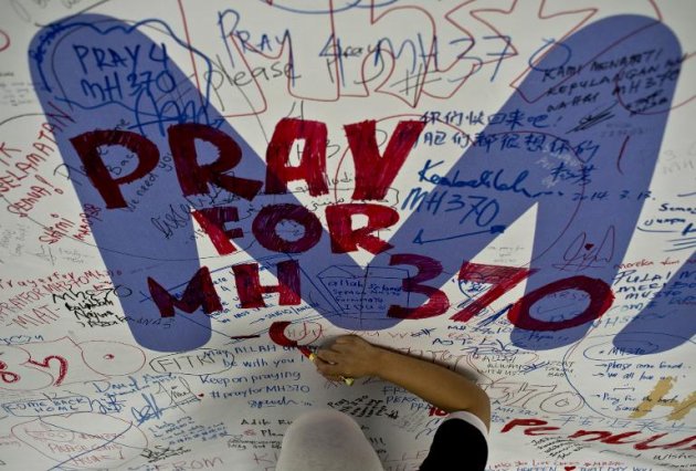 Funcionário da Malaysia Airlines escreve uma mensagem para os passageiros do voo MH370, aeroporto internacional de Kuala Lumpur, em Sepang, na Malásia