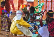Usando traje especial, um trabalhador da ONG Médicos sem Fronteira, alimenta uma criança vítima do Ebola em Kailahun, Serra Leoa