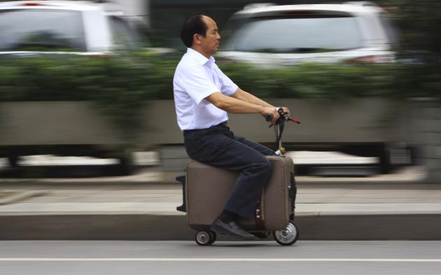 He Liang rides his home-made suitcase vehicle along a street in Changsha