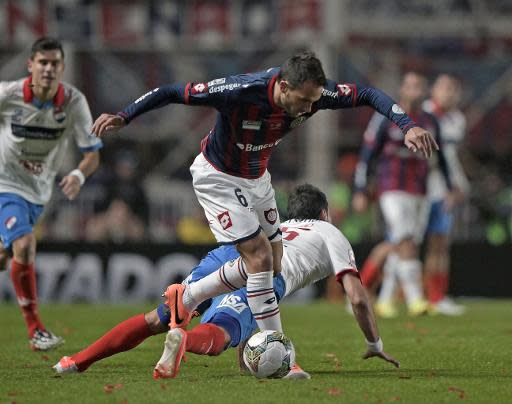 Santiago Gentiletti (C), de San Lorenzo, intenta esapar de la marca de los hombres de Nacional de Paraguay, en partido de vuelta de la última de la Libertadores-2014