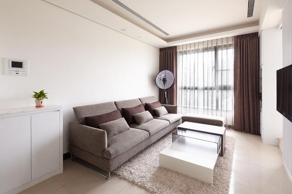 客廳以白色系為基調，搭配大地色系的軟件，加上落地窗迎來的自然光線，整體氣氛清爽舒適。