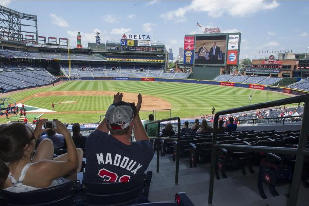 Fans Scott Grazzilla, right, and Ashley Grazilla watch Greg Maddux on the big screen at Turner Field as he is inducted into the Baseball Hall of Fame, before a baseball game between the Atlanta Braves
