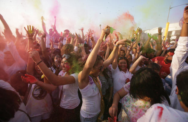 People throw colored powder as they dance to celebrate the Holi festival in suburban Pasay, south of Manila, Philippines, Sunday March 16, 2014. The event is led by Indian nationals as they mark Holi,