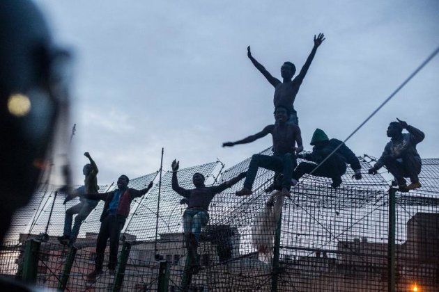 Inmigrantes clandestinos celebran su ascenso a la valla fronteriza que separa Melilla de Marruecos, el 28 de marzo de 2014