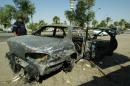 An Iraqi looks at a burnt car on the site where Blackwater guards who were escorting US embassy officials opened fire in the western Baghdad neighbourhood of Yarmukh, September 24, 2007