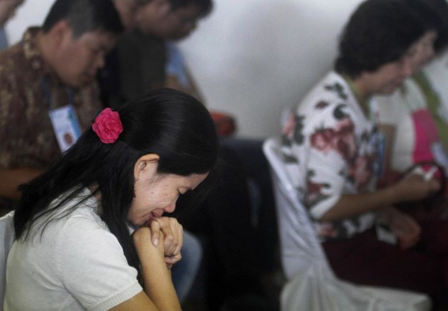 A relative of passengers of the missing AirAsia flight QZ8501 weeps as she prays at the crisis center at Juanda International Airport in Surabaya, East Java, Indonesia, Tuesday, Dec. 30, 2014. More planes will be in the air and more ships on the sea Tuesday hunting for AirAsia Flight 8501 in a widening search off Indonesia that has dragged into a third day without any solid leads. Flight 8501 vanished Sunday in airspace thick with storm clouds on its way from Surabaya, Indonesia, to Singapore. (AP Photo/Trisnadi Marjan)