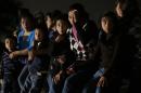 FILE - This June 25, 2014, file photo shows a group of immigrants from Honduras and El Salvador who crossed the U.S.-Mexico border illegally are stopped in Granjeno, Texas. The influx at the border is largely families with children or by minors traveling alone. (AP Photo/Eric Gay, File)