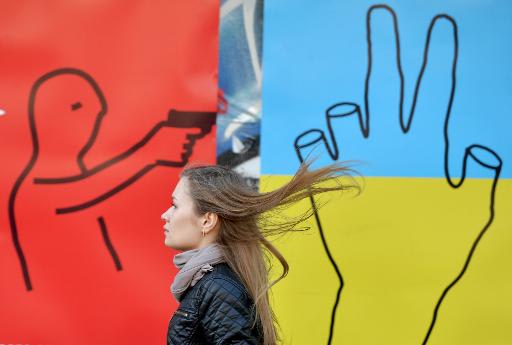 Una mujer ucraniana pasa junto a un mural anti-guerra en el centro de la capital del país, Kiev, el 21 de marzo de 2014 (AFP/Archivos | Sergei Supinsky)