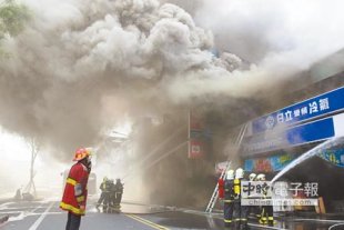 宜蘭市知名電器行遭到客戶潑汽油縱火，2樓冒出陣陣悶燒濃煙，消防隊員以水柱降溫滅火。（簡榮輝攝）