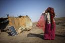 A labourer, who works in a salt pan, covers her face beside a solar panel outside a shelter in Little Rann of Kutch in the western Indian state of Gujarat