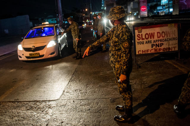 Police officers monitor the entry and exit of vehicles along a major thoroughfare in Quezon City, Philippines following the implementation of community quarantine in the whole of Metro Manila at midnight of March 15, 2020. (Photo by Lisa Marie David/NurPhoto via Getty Images)