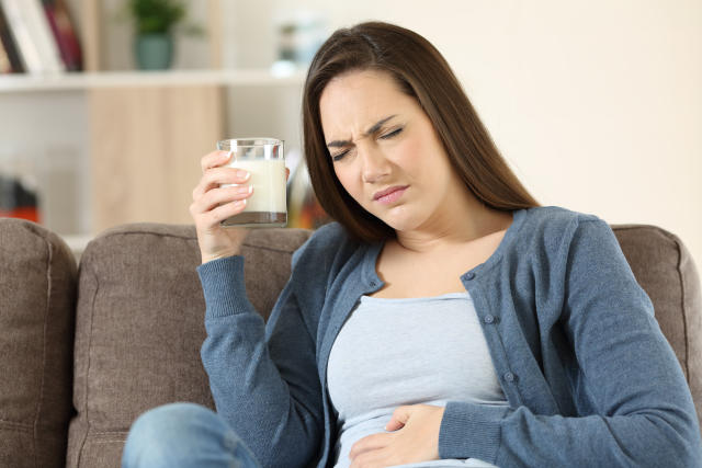 Woman suffering lactose intolerance sitting on a couch in the living room at home