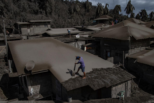 Men clean rooftops of ash from the recent eruption. | Ezra Acayan—Getty Images