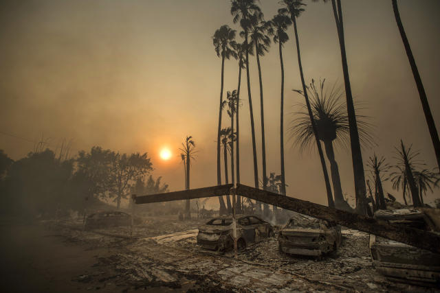 FILE - In this Dec. 5, 2017 file photo, smoke rises behind a destroyed apartment complex as a the Thomas wildfire burns in Ventura, Calif. In the last year, fires have devastated neighborhoods in the Northern California wine country city of Santa Rosa, the Southern California beach city of Ventura and, now, the inland city of Redding. Hotter weather from changing climates is drying out vegetation, creating more intense fires that spread quickly from rural areas to city subdivisions, climate and fire experts say. But they also blame cities for expanding into previously undeveloped areas susceptible to fire. (AP Photo/Noah Berger, File)