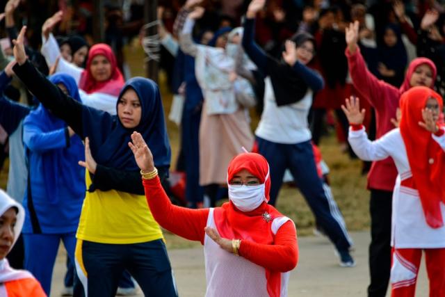 Women wearing face masks exercise at a playground in Banda Aceh, Indonesia on Feb. 2, 2020. | CHAIDEER MAHYUDDIN—AFP/Getty Images